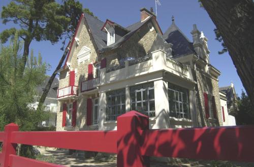 une grande maison avec une clôture rouge devant elle dans l'établissement Hôtel Lutétia & Spa, à La Baule