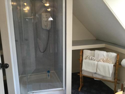 a bathroom with a shower and a chair in a attic at Three-Bedroom Old Cottage Free Parking in Inverness