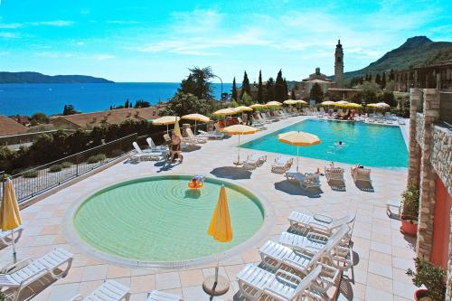 a large swimming pool with chairs and umbrellas at Residence Borgo Dei Limoni - Appartamenti con Garage in Gargnano