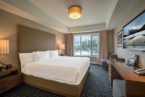 a hotel room with a bed and a desk and a window at The Malcolm Hotel in Canmore