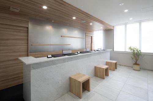 a lobby with a reception counter with benches and sidx sidx sidx at Shizutetsu Hotel Prezio Hakataekimae in Fukuoka