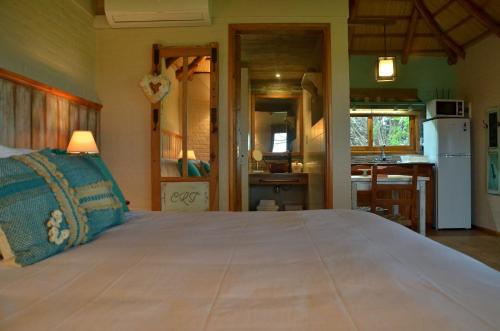 a bedroom with a large bed and a kitchen at CABAÑA LA TOSCANA in Carmelo