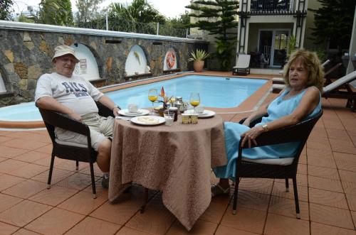a man and woman sitting at a table next to a pool at Villa Narmada in Grand Baie