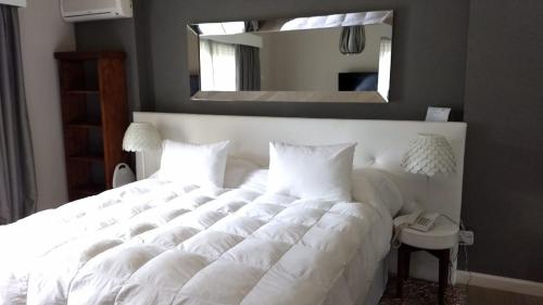a white bed in a bedroom with a mirror at Apartamento Forest Lagoon Punta Del Este in Punta del Este
