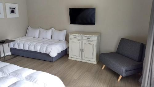a bedroom with a bed and a chair and a tv at Apartamento Forest Lagoon Punta Del Este in Punta del Este