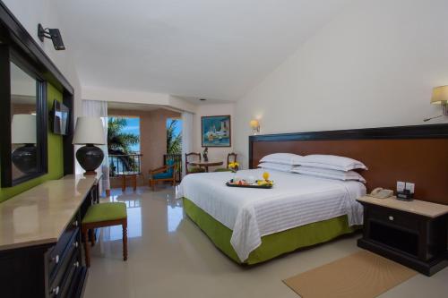 a bedroom with a large bed and a dining room at Barceló Huatulco in Santa Cruz Huatulco