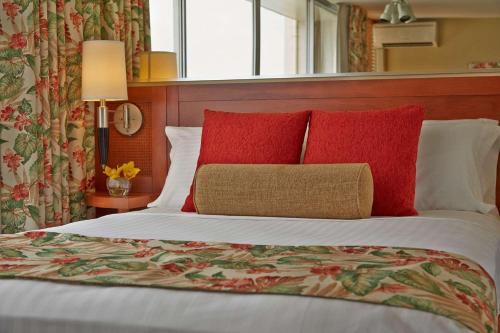a bedroom with a bed with red pillows at Pacific Monarch Hotel in Honolulu
