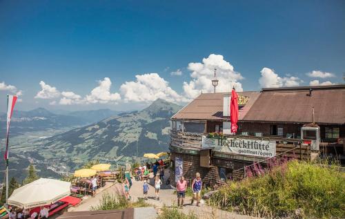 un groupe de personnes debout devant un bâtiment dans l'établissement Hocheckhuette On Top of the Kitzbuehel Hahnenkamm Mountain, à Kitzbühel