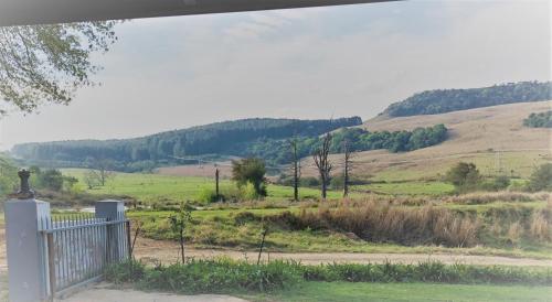 a fence in a field with a hill in the background at Old Balgowan Farm Cottage in Balgowan