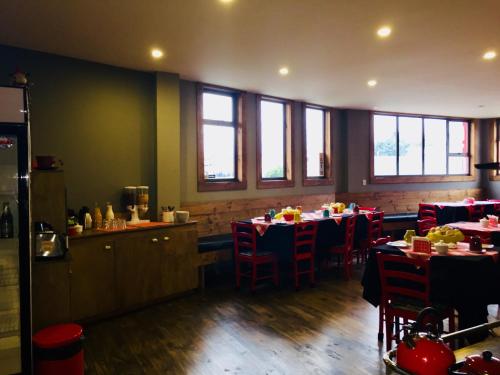 a dining room with tables and chairs and windows at Hostal Esquina Patagónica in Coihaique
