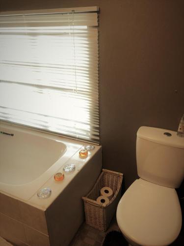a bathroom with a tub and a toilet and a window at Old Balgowan Farm Cottage in Balgowan