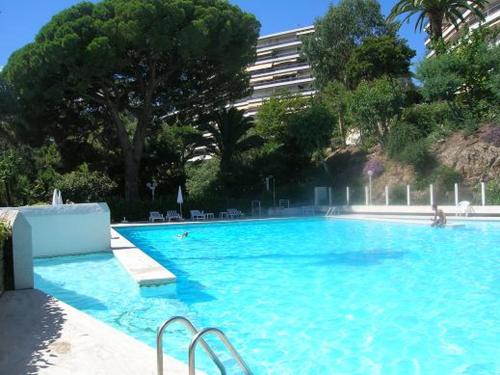une grande piscine bleue avec des arbres et un bâtiment dans l'établissement La Mirandole 3 pièces vue mer, au Golfe-Juan