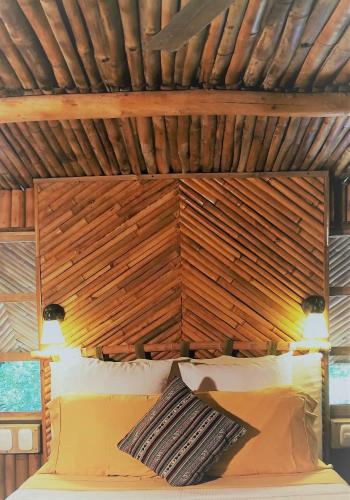a bed in a room with a wooden ceiling at Tortugal Boutique River Lodge in Rio Dulce