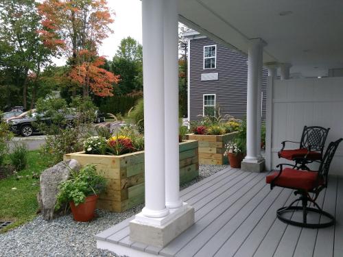 a porch with a chair and flowers on a house at The Inn on Mount Desert in Bar Harbor