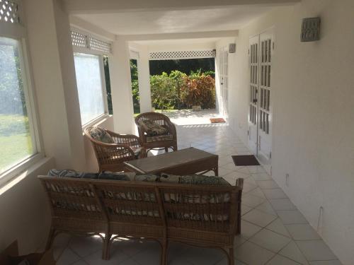 a living room with chairs and a table and windows at Spacious White House Villa 1 minute to sandy beaches in Saint James