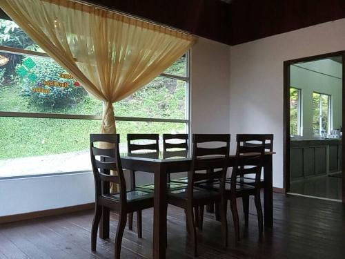 ein Esszimmer mit einem Tisch, Stühlen und einem Fenster in der Unterkunft J Residence in Kampong Kundassan