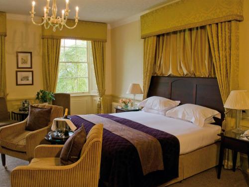 a bedroom with a large bed and a chandelier at Ansty Hall in Coventry