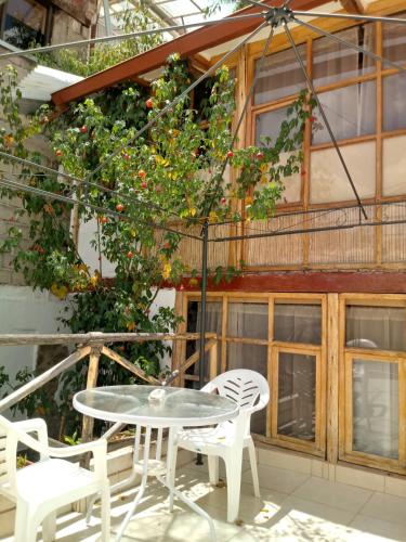 a patio with a table and chairs and an orange tree at Casa De Mama Cusco - The Treehouse in Cusco