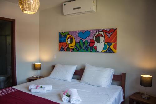 a bedroom with a bed with towels on it at Aldeia das flores in Pipa