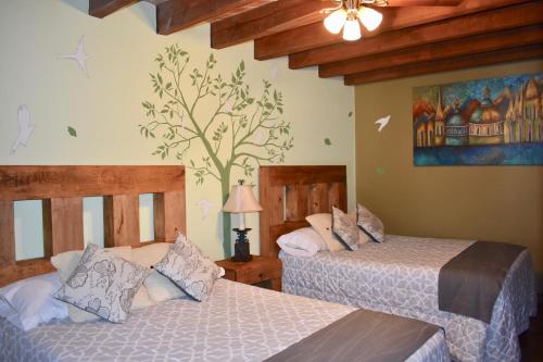 a bedroom with two beds and a painting on the wall at Hotel Ana Catalina and Suites in San Miguel de Allende