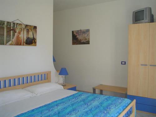 ein Schlafzimmer mit einem Bett und einem TV an der Wand in der Unterkunft B&B Brezza Marina & Ristorante Shoreline in Pozzallo