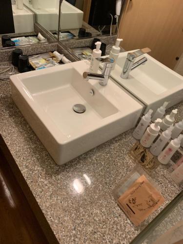 大阪市にあるホテル ビ・ゼン シマノウチの白いバスルームの洗面台(花崗岩のカウンタートップに座る)