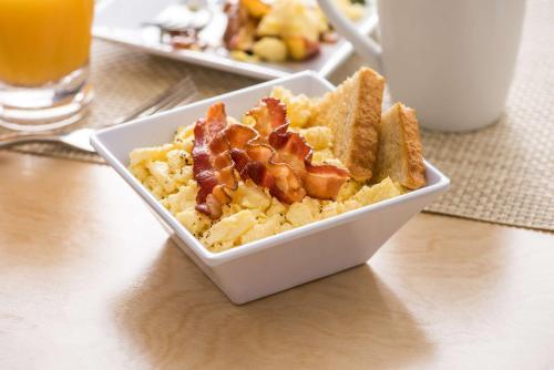 a bowl of food with bacon and toast on a table at Hyatt Place Miami Airport East in Miami