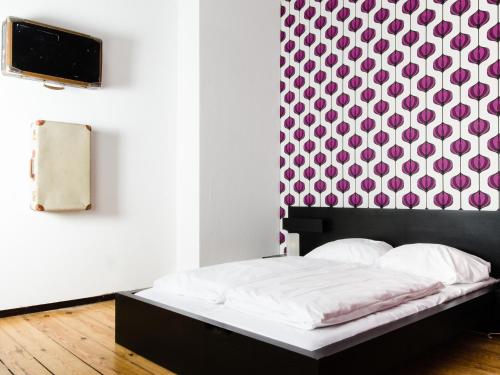 a bed in a room with a wall with avertisement for at Lette'm Sleep Berlin in Berlin