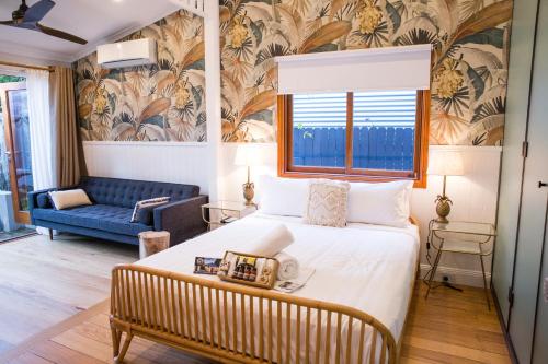 a bedroom with a large bed and a blue couch at Bayhaven Lodge in Byron Bay