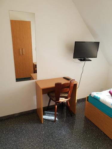 a room with a desk and a bed and a mirror at Pension Haus Baron 1 Neckarau in Mannheim