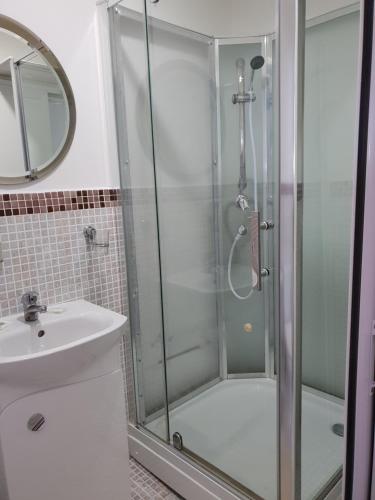 a shower with a glass door next to a sink at Pension Haus Baron 1 Neckarau in Mannheim