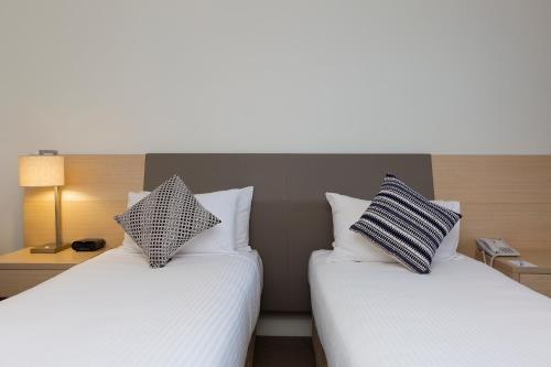 a hotel room with two beds and two lamps at Sage Hotel Wollongong in Wollongong
