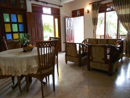 comedor con mesa, sillas y ventanas en Accoma Villa, en Hikkaduwa
