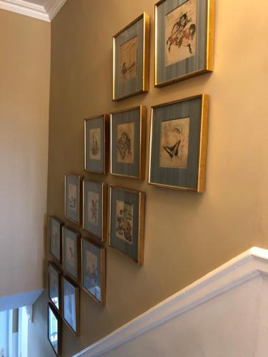 a group of framed pictures on a wall at Wynberg House Bed & Breakfast Swansea in Swansea