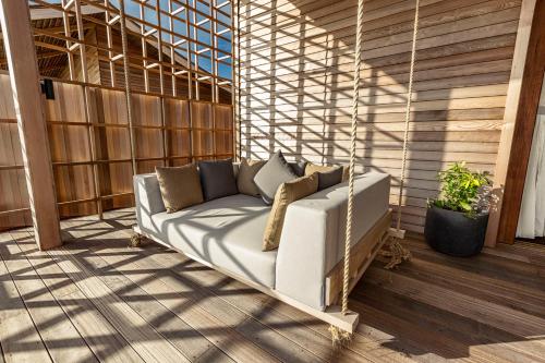 a couch is sitting on a porch at Kudadoo Maldives Private Island – Luxury All inclusive in Lhaviyani Atoll