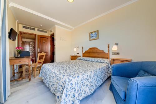 a bedroom with a bed and a blue couch at Hotel La Española in Chipiona