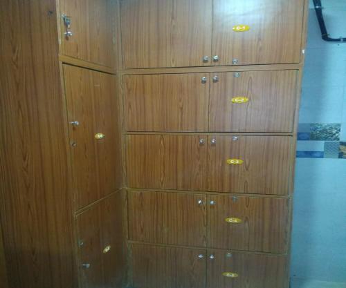 a wooden cabinet with many drawers in a room at Ahlan Green Apple Dormitory in Mumbai