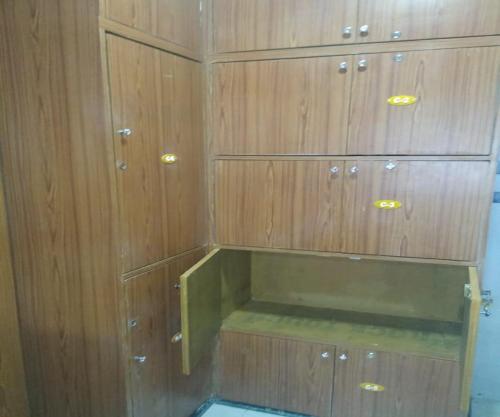 a cupboard with wooden cabinets in a room at Ahlan Green Apple Dormitory in Mumbai