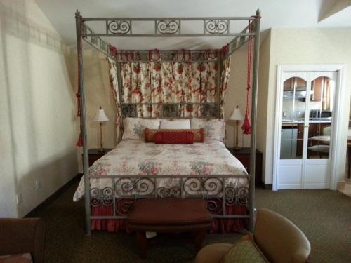 a bedroom with a canopy bed and a chair at The Vendange Carmel Inn & Suites in Carmel