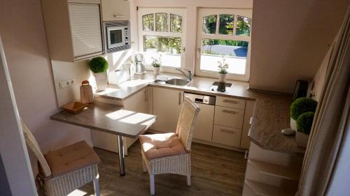eine Küche mit einem Tisch, Stühlen und einem Waschbecken in der Unterkunft Appartementhaus Vor dem Moor in Bad Zwischenahn