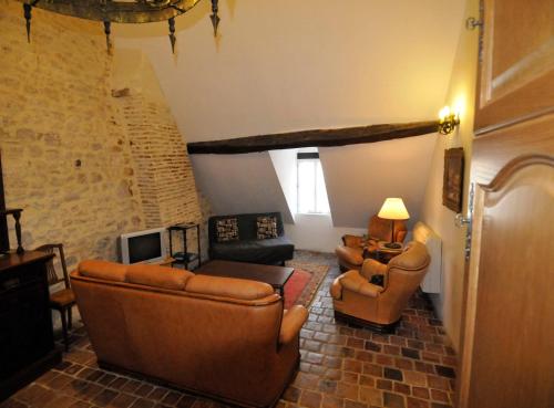 a living room with leather couches and a tv at Le Passage in La Charité-sur-Loire