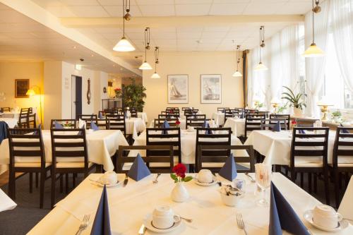 una sala da pranzo con tavoli e sedie bianchi di Hotel Senator Marina a Wedel