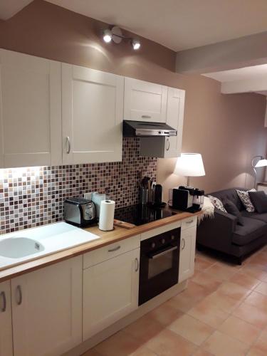 une cuisine avec des armoires blanches et un salon dans l'établissement Maison de village, à Bagnols-en-Forêt