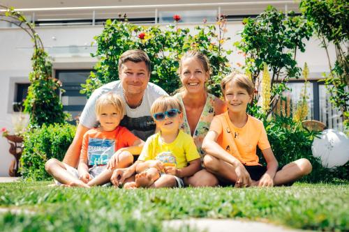 a family sitting on the grass in the yard at Apart Sunshine in Ladis