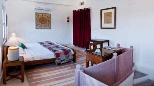 a bedroom with a bed and a table with a lamp at Neemrana's - Hill Fort - Kesroli in Alwar