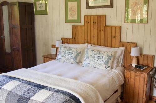 Schlafzimmer mit einem großen Bett mit einem Kopfteil aus Holz in der Unterkunft Pear Tree Cottage in Stormsrivier