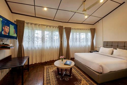 a bedroom with a bed and a table and a tv at The Heritage Club - Tripura Castle Hotel and Spa in Shillong