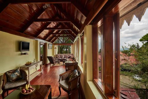 a living room with a large window and a couch at The Heritage Club - Tripura Castle Hotel and Spa in Shillong