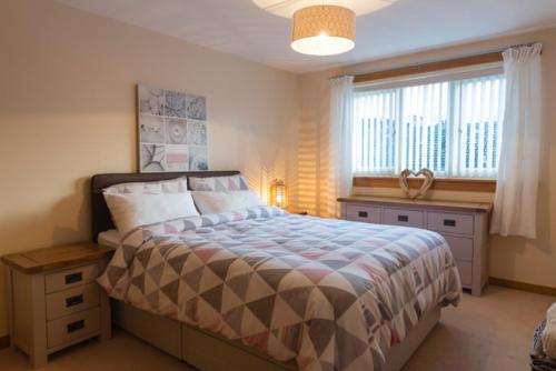 a bedroom with a large bed and a window at Modern apt, amazing harbour views, wifi & parking in Musselburgh