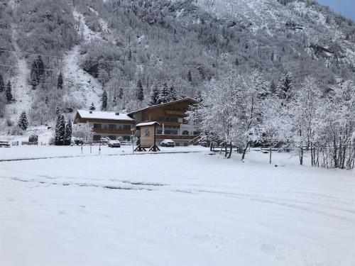 een met sneeuw bedekt veld met een huis op de achtergrond bij Hotel Künstleralm in Kaprun